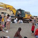 Ruspa Al Lavoro Sulla Spiaggia Gialla Di Ostia Senza Misure Di Sicurezza Per Bagnanti: Scoppia La Polemica